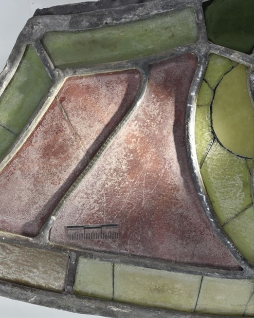 A close up image of a stained glass panel. One of the lead cames has an unusual long mark on the surface.